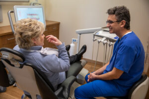 Dr. Constantin talking to a patient about how her dental implant procedure will be cost-effective.