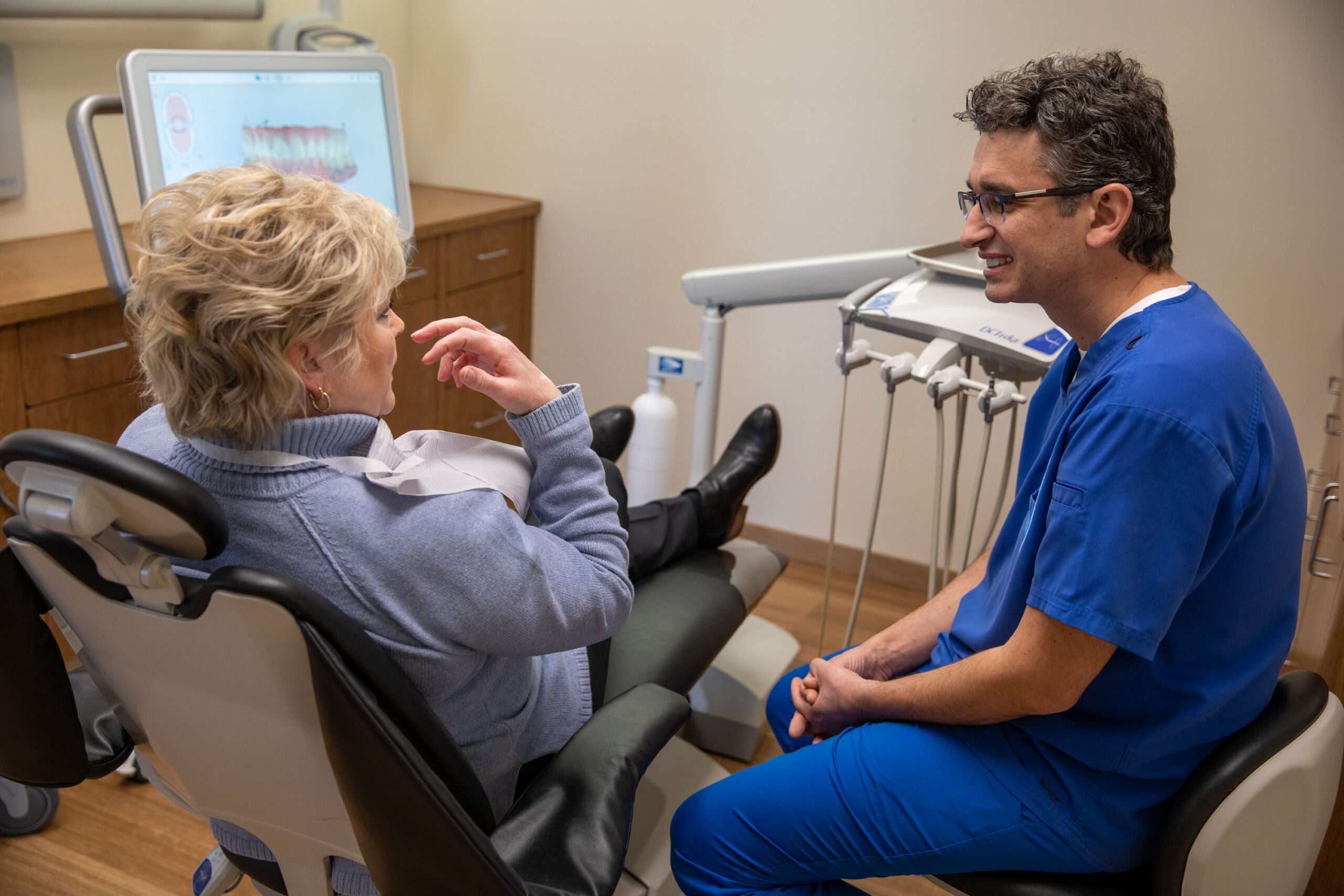 Dr. Constantin talking to a patient about how her dental implant procedure will be cost-effective.