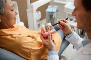 a closeup of a dentist showing a tooth model